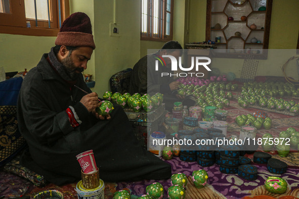 Showkat Haji (left), a Kashmiri artisan, paints Christmas gift items at the workshop before sending them to the market ahead of Christmas ce...