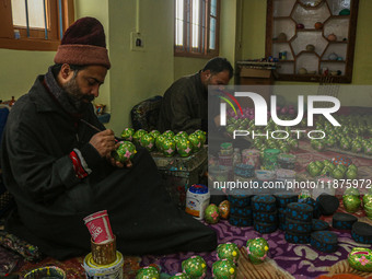 Showkat Haji (left), a Kashmiri artisan, paints Christmas gift items at the workshop before sending them to the market ahead of Christmas ce...