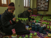 Showkat Haji (left), a Kashmiri artisan, paints Christmas gift items at the workshop before sending them to the market ahead of Christmas ce...