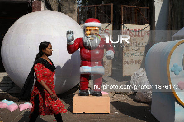 A woman walks past a giant model of Santa Claus made of polystyrene at a roadside workshop ahead of Christmas celebrations in Kolkata, India...