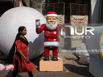 A woman walks past a giant model of Santa Claus made of polystyrene at a roadside workshop ahead of Christmas celebrations in Kolkata, India...