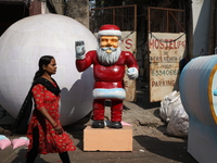 A woman walks past a giant model of Santa Claus made of polystyrene at a roadside workshop ahead of Christmas celebrations in Kolkata, India...