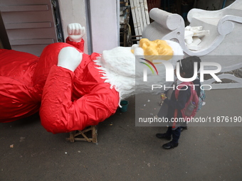 School students look at a giant model of Santa Claus made of polystyrene at a roadside workshop ahead of Christmas celebrations in Kolkata,...