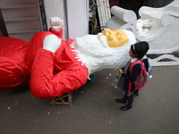 School students look at a giant model of Santa Claus made of polystyrene at a roadside workshop ahead of Christmas celebrations in Kolkata,...