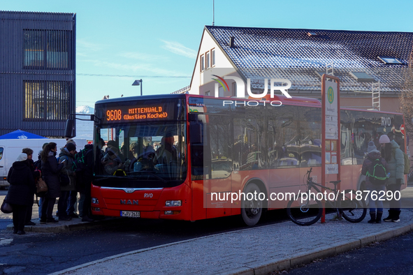 Passengers board the regional bus at Garmisch-Partenkirchen Train Station in Bavaria, Germany, on December 13, 2024. A bright red regional b...