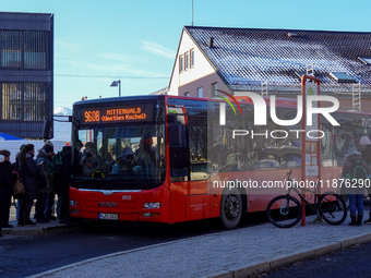 Passengers board the regional bus at Garmisch-Partenkirchen Train Station in Bavaria, Germany, on December 13, 2024. A bright red regional b...