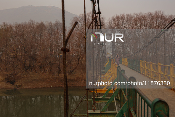 A girl walks on a metal pedestrian bridge on a cold winter day in Baramulla, Jammu and Kashmir, India, on December 17, 2024. 