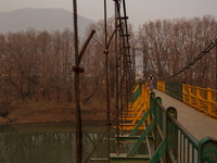 A girl walks on a metal pedestrian bridge on a cold winter day in Baramulla, Jammu and Kashmir, India, on December 17, 2024. (