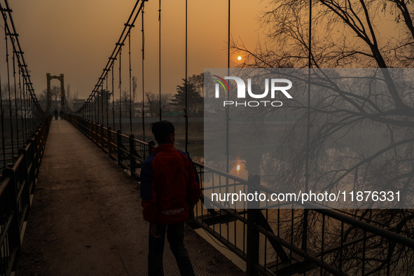 A boy walks as the sun appears on a cold winter day in Baramulla, Jammu and Kashmir, India, on December 17, 2024. 