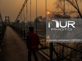 A boy walks as the sun appears on a cold winter day in Baramulla, Jammu and Kashmir, India, on December 17, 2024. (