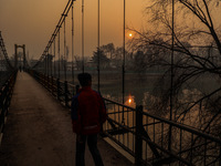 A boy walks as the sun appears on a cold winter day in Baramulla, Jammu and Kashmir, India, on December 17, 2024. (