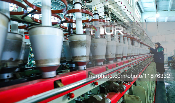 A worker checks the operation of a double-twist machine producing nickel electrolytic composite diaphragm at a textile production line in Zh...