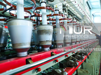 A worker checks the operation of a double-twist machine producing nickel electrolytic composite diaphragm at a textile production line in Zh...