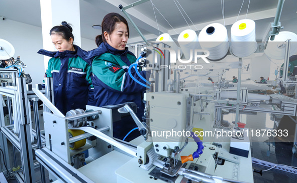 Staff members check the production of air filter bags at an automated production line for textile tube filter bags in Zhangye, China, on Dec...