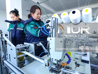 Staff members check the production of air filter bags at an automated production line for textile tube filter bags in Zhangye, China, on Dec...