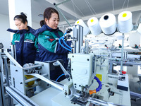 Staff members check the production of air filter bags at an automated production line for textile tube filter bags in Zhangye, China, on Dec...