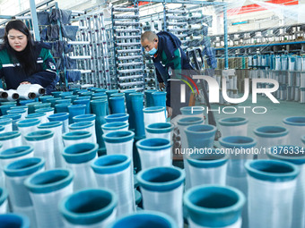 Workers sort warp threads for industrial textiles at a textile production line in Zhangye, China, on December 17, 2024. (