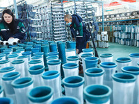 Workers sort warp threads for industrial textiles at a textile production line in Zhangye, China, on December 17, 2024. (