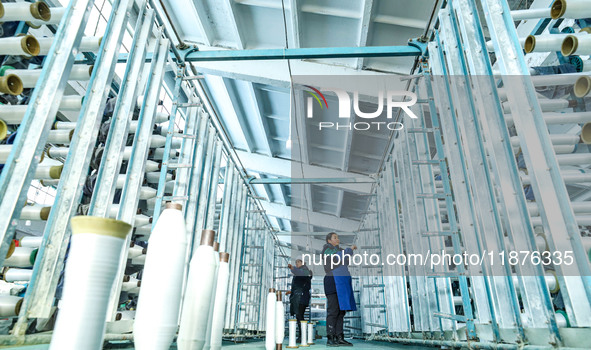 Workers sort warp threads for industrial textiles at a textile production line in Zhangye, China, on December 17, 2024. 