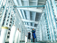 Workers sort warp threads for industrial textiles at a textile production line in Zhangye, China, on December 17, 2024. (