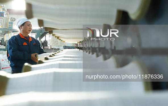 Workers sort warp threads for industrial textiles at a textile production line in Zhangye, China, on December 17, 2024. 