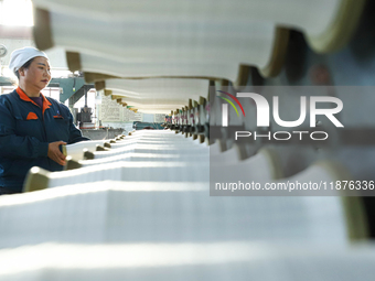 Workers sort warp threads for industrial textiles at a textile production line in Zhangye, China, on December 17, 2024. (