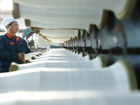 Workers sort warp threads for industrial textiles at a textile production line in Zhangye, China, on December 17, 2024. (