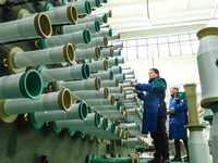 Workers sort warp threads for industrial textiles at a textile production line in Zhangye, China, on December 17, 2024. (