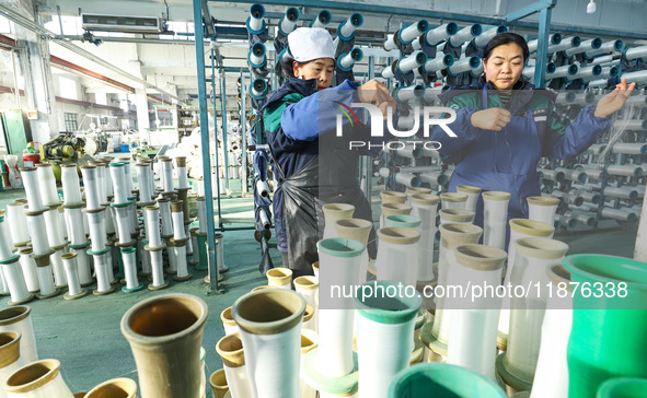 Workers sort warp threads for industrial textiles at a textile production line in Zhangye, China, on December 17, 2024. 