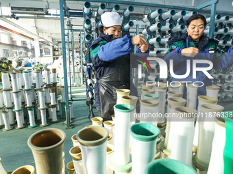 Workers sort warp threads for industrial textiles at a textile production line in Zhangye, China, on December 17, 2024. (