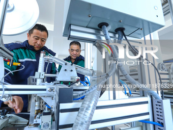 Workers check the production of air filter bags at an automated production line for textile tube filter bags in Zhangye, China, on December...