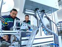 Workers check the production of air filter bags at an automated production line for textile tube filter bags in Zhangye, China, on December...