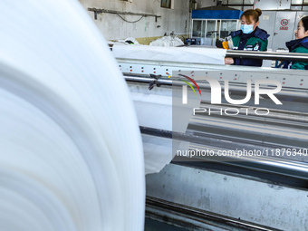 Workers work on hot-pressed rolls for industrial textiles at a textile production line in Zhangye, China, on December 17, 2024. (