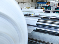 Workers work on hot-pressed rolls for industrial textiles at a textile production line in Zhangye, China, on December 17, 2024. (