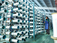 Workers sort warp threads for industrial textiles at a textile production line in Zhangye, China, on December 17, 2024. (