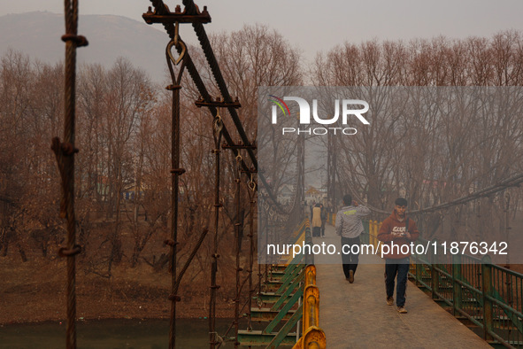 People walk on a footbridge on a cold winter day in Baramulla, Jammu and Kashmir, India, on December 17, 2024. 