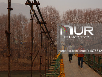 People walk on a footbridge on a cold winter day in Baramulla, Jammu and Kashmir, India, on December 17, 2024. (