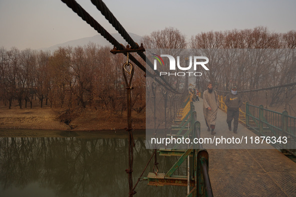 People walk on a footbridge on a cold winter day in Baramulla, Jammu and Kashmir, India, on December 17, 2024. 