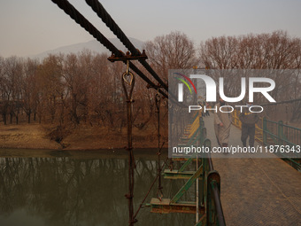 People walk on a footbridge on a cold winter day in Baramulla, Jammu and Kashmir, India, on December 17, 2024. (