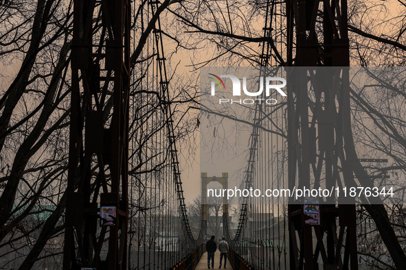 People walk on a footbridge on a cold winter day in Baramulla, Jammu and Kashmir, India, on December 17, 2024. 