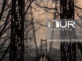 People walk on a footbridge on a cold winter day in Baramulla, Jammu and Kashmir, India, on December 17, 2024. (