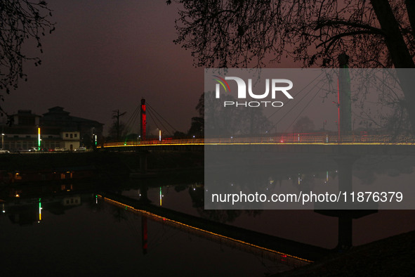 People walk over the river Jhelum bridge on a cold evening in Srinagar, Jammu and Kashmir, on December 17, 2024. Cold wave conditions intens...