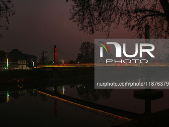 People walk over the river Jhelum bridge on a cold evening in Srinagar, Jammu and Kashmir, on December 17, 2024. Cold wave conditions intens...