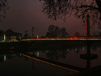 People walk over the river Jhelum bridge on a cold evening in Srinagar, Jammu and Kashmir, on December 17, 2024. Cold wave conditions intens...