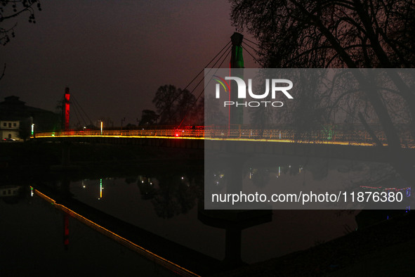 People walk over the river Jhelum bridge on a cold evening in Srinagar, Jammu and Kashmir, on December 17, 2024. Cold wave conditions intens...