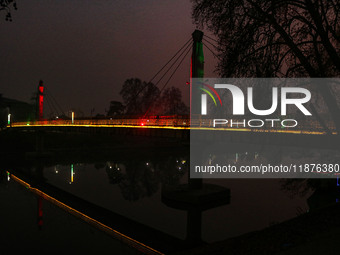 People walk over the river Jhelum bridge on a cold evening in Srinagar, Jammu and Kashmir, on December 17, 2024. Cold wave conditions intens...