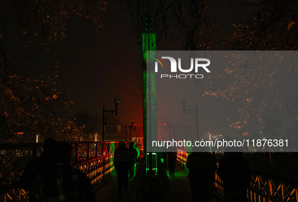 People walk over the river Jhelum bridge on a cold evening in Srinagar, Jammu and Kashmir, on December 17, 2024. Cold wave conditions intens...