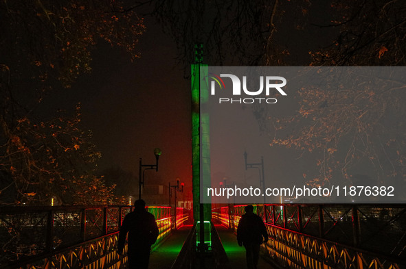 People walk over the river Jhelum bridge on a cold evening in Srinagar, Jammu and Kashmir, on December 17, 2024. Cold wave conditions intens...