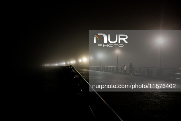 Runners move through dense fog covering Liberty State Park following rainfall in Jersey City, NJ, U.S., on December 16, 2024. 