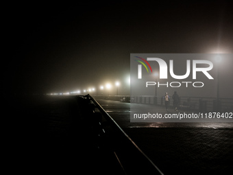 Runners move through dense fog covering Liberty State Park following rainfall in Jersey City, NJ, U.S., on December 16, 2024. (